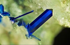 two blue glass pieces sitting on top of a rock