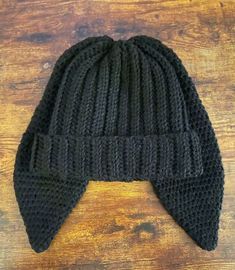 a black knitted beanie hat on top of a wooden table