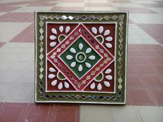 a decorative tile with white and green designs on the outside, sitting on a tiled floor