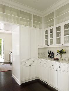 a kitchen with white cabinets and wooden floors