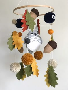 an animal mobile is hanging from the ceiling with leaves and acorns on it