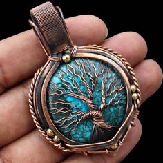 a person holding a pendant with a tree on it