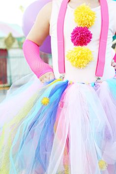 a woman wearing a colorful dress and holding onto her hands with balloons in the background