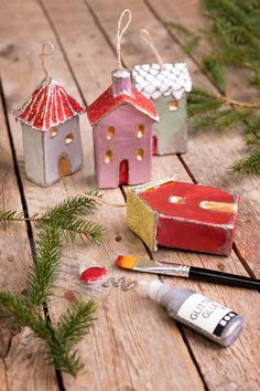 some little houses are sitting on a wooden table with paint and brushes next to them