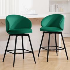 two green chairs sitting next to each other on top of a hard wood floored floor