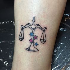 a tattoo on the leg of a woman with a scale and stars in front of her