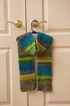 a knitted scarf hanging from a hook on a door