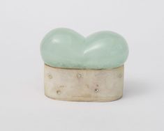 a green heart shaped object sitting on top of a white surface