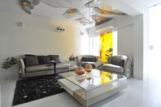 a living room with couches, chairs and a glass table in the middle of it