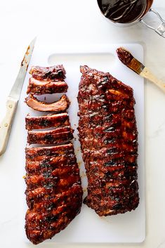 two ribs on a cutting board next to a knife