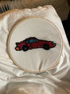 a red car embroidered onto a white cloth