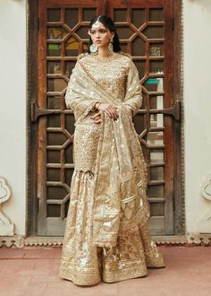 Pakistani Wedding Dress in Kameez Gharara Style is an epitome of beauty. This attire adorned with Sequins, Beads, Motifs, and Tilla is available Online. Wedding Sharara With Dabka Work In Jamawar, Gold Sharara With Intricate Embroidery For Eid, Gold Sharara With Dabka For Reception, Chinon Sharara With Dabka For Reception, Anarkali Sharara With Intricate Embroidery In Jamawar, Jamawar Sharara With Resham Embroidery For Reception, Anarkali Style Jamawar Sharara For Wedding, Gold Jamawar Sharara With Dabka Work, Anarkali Jamawar Sharara For Wedding