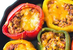 several stuffed peppers in a black pan with cheese on the top and ground beef inside