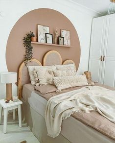 a bed with white sheets and pillows in a bedroom next to a wall mounted plant