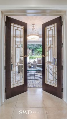 an open door leading to a living room with a chandelier hanging from the ceiling