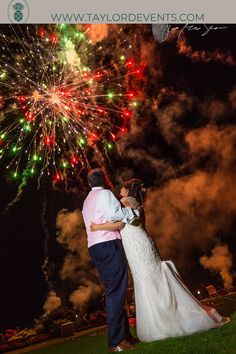 a bride and groom standing in front of fireworks