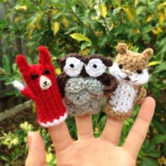 three small knitted animals sitting on top of each other's fingernails