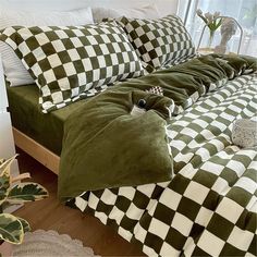 a bed with green and white checkered comforters on it, next to a window