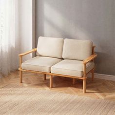 a wooden couch sitting on top of a hard wood floor next to a white wall