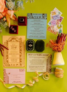 the wedding stationery is laid out on a green surface with flowers and other items