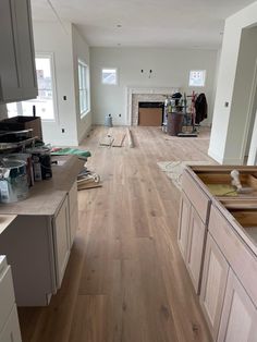 an empty kitchen with hard wood flooring and white cabinets in the middle of it