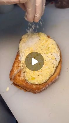 someone is sprinkling cheese on top of a bagel with an egg on it