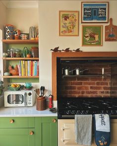 a kitchen with green cabinets and an oven in the center, surrounded by pictures on the wall