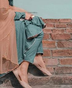 a woman sitting on top of a brick wall next to a brown and blue blanket