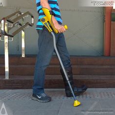 a man using a yellow and black electric lawn mower on the side of a building