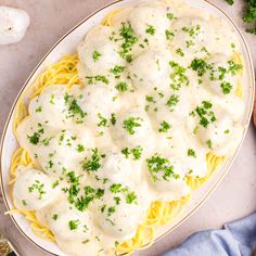 a white plate topped with pasta covered in cheese sauce and garnished with parsley