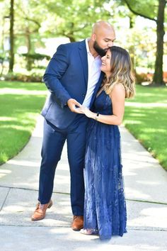 a man in a blue suit and woman in a blue dress standing on a sidewalk