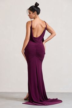 a woman in a long purple dress with her back to the camera, looking down