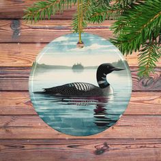 a ceramic ornament with a bird on it's side hanging from a pine tree