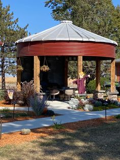 a red and white gazebo sitting in the middle of a park next to trees