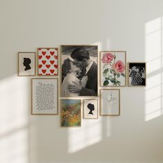 a white wall with many framed photos and pictures on it, including a man kissing a woman