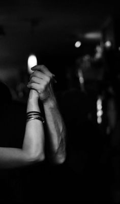 black and white photograph of two people holding each other's hands in the dark