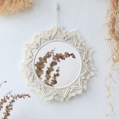 a white doily hanging from a wall with dried flowers in the mirror and other items around it