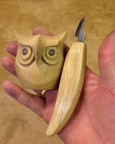 a hand holding a small wooden owl with a knife in it's left hand