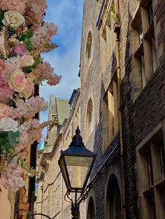 a street light sitting next to a tall brick building with lots of flowers on it