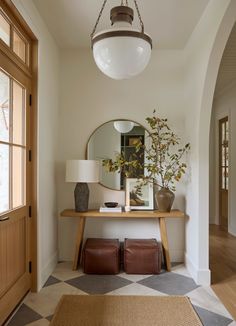 a foyer with a mirror, lamp and bench