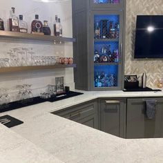 a kitchen counter with wine glasses and liquor bottles on the shelves in front of it