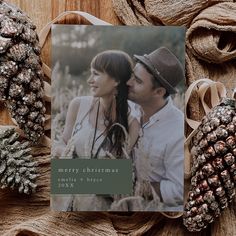 a christmas card with an image of a man and woman on it next to pine cones