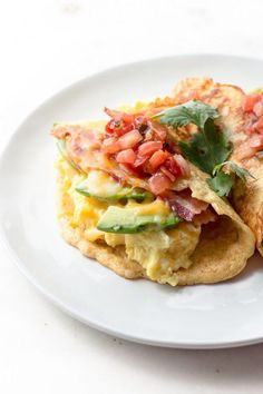 an omelet with bacon, tomatoes and avocado is on a white plate