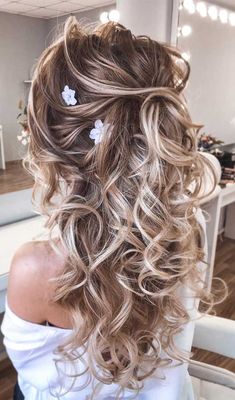 the back of a woman's head with curly hair and flowers in her hair