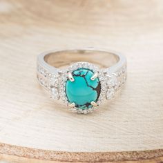 Product Details Ring Style: "Fancy" is an oval turquoise women's engagement ring with a diamond halo and diamond accents. Many other center stone options available upon request. Center Stone: 10x8mm Oval Turquoise Materials: 14K gold engagement ring featuring a turquoise center stone and 1.16 CTW accent diamonds. Customizable: Because each ring is handcrafted to order, we can customize yours using unique materials, gemstones, or design features, often without any added cost! We can even use pers Turquoise Diamond Rings With Center Stone, Oval Turquoise Diamond Ring For Wedding, Oval Turquoise Ring With Diamond Accents For Anniversary, Oval Turquoise Ring With Center Stone For Anniversary, Oval Turquoise Ring With Diamond Accents, Elegant Oval Turquoise Ring With Center Stone, Oval Turquoise Jewelry With Halo Setting, Turquoise Oval Jewelry With Halo Setting, Turquoise Oval Ring With Halo Setting