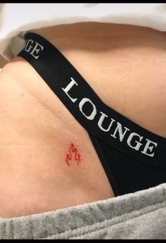 a woman's stomach with the words lounge on it and a red heart tattoo