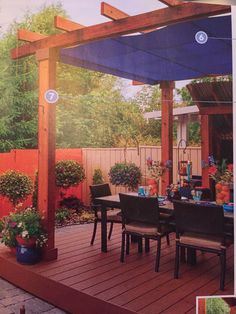 an outdoor dining area with wooden decking and pergolated patio furniture, surrounded by trees