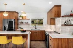 a kitchen with wooden cabinets and yellow stools next to an island counter top in the middle