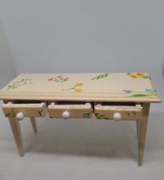 a small wooden table with two drawers on each side and flowers painted on the top