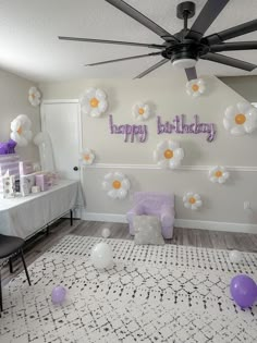 a birthday party with balloons and flowers on the wall, chairs and table in the background